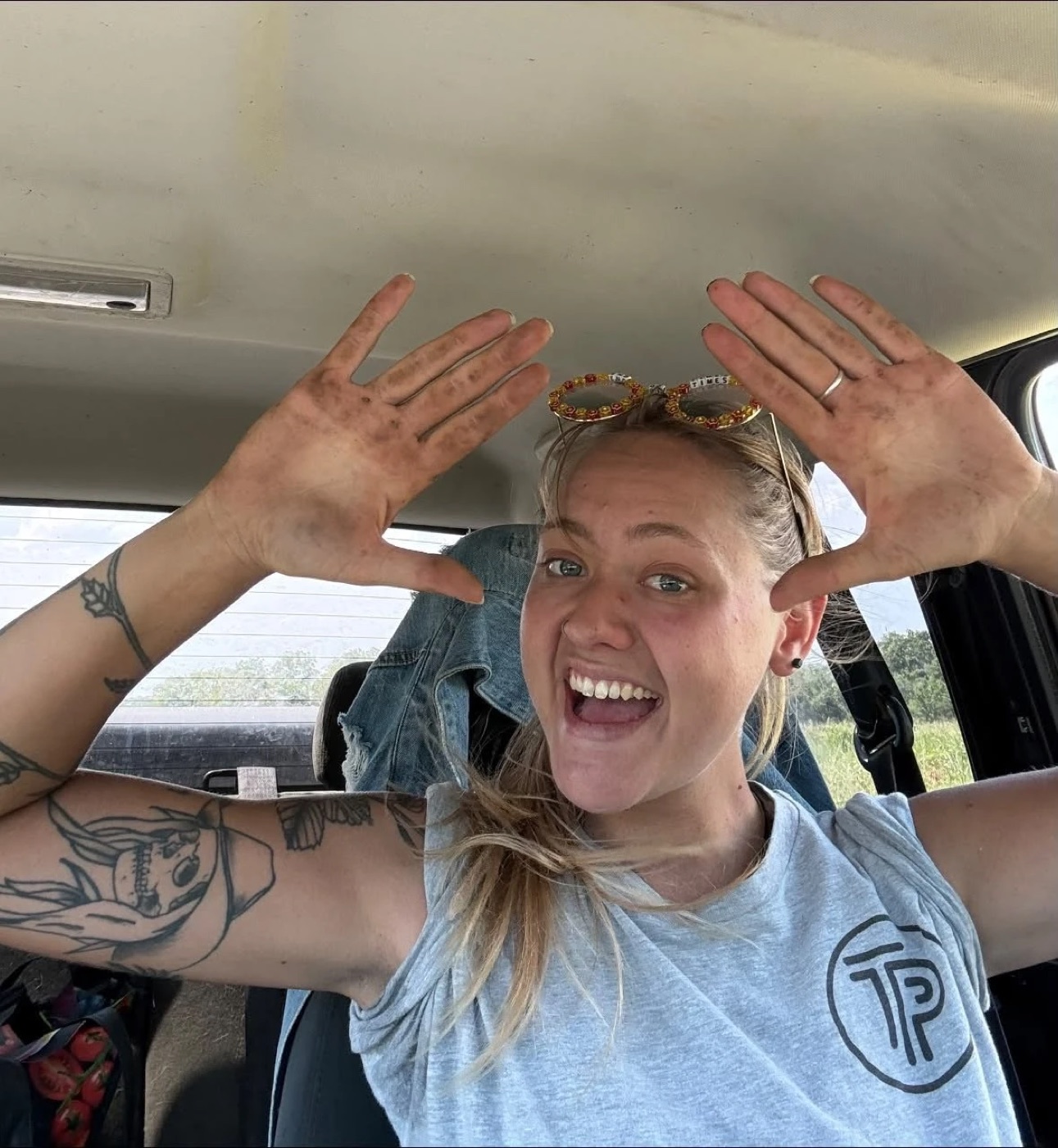 Krislyn Barker grinning in her truck, both palms up and covered in work dirt
